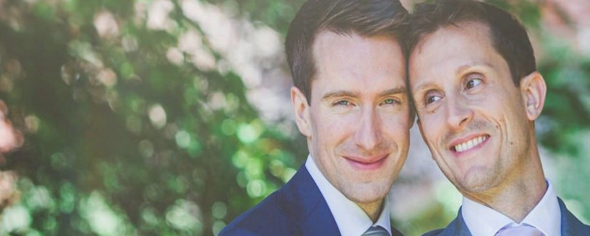 Two men in suits getting married to each other